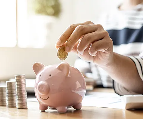 A person putting a coin on a piggy bank.
